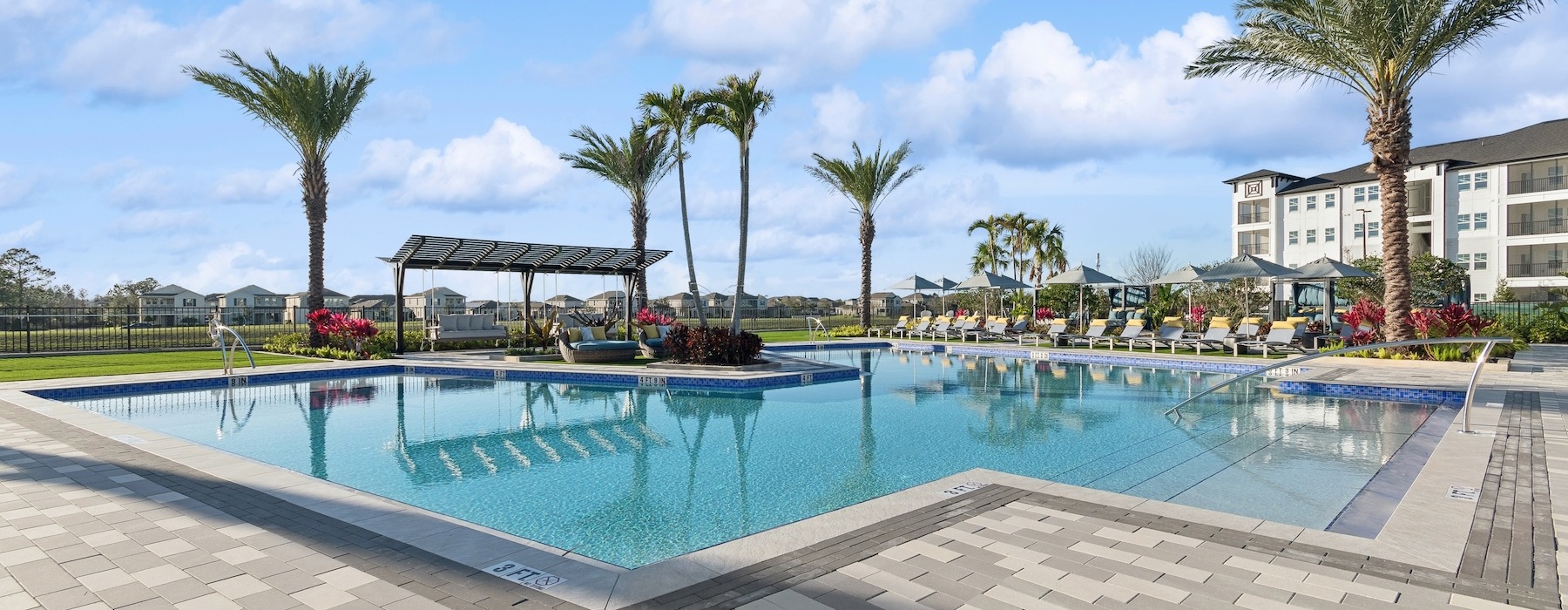 a pool with palm trees and a building in the background