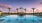 a pool with palm trees and a sunset