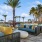 a patio with palm trees and lounge seating