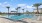 a pool with palm trees and building in the back