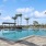 a pool with palm trees and building in the back